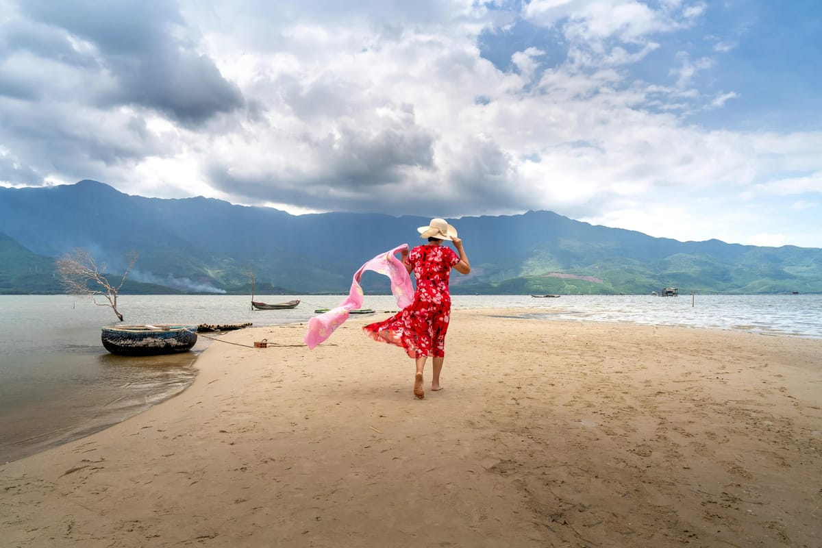 Woman in red dress on beach with pink scarf