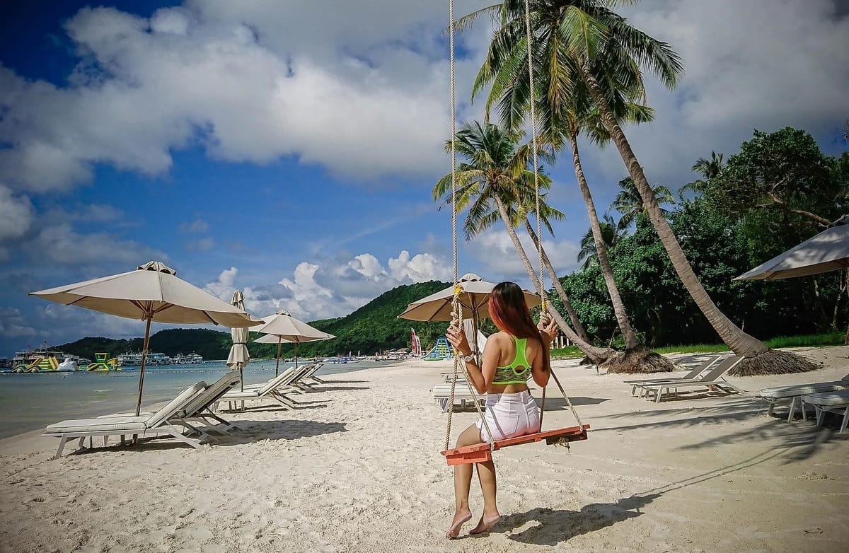 Woman on beach swing enjoying sun