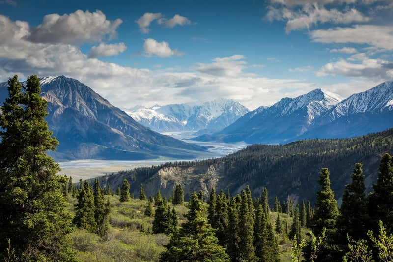 Snow-capped mountains, lake-filled valley, and forested landscape