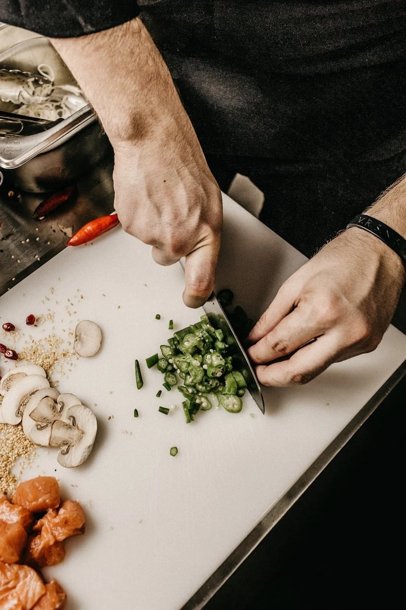 man cutting green onions on cutting board
